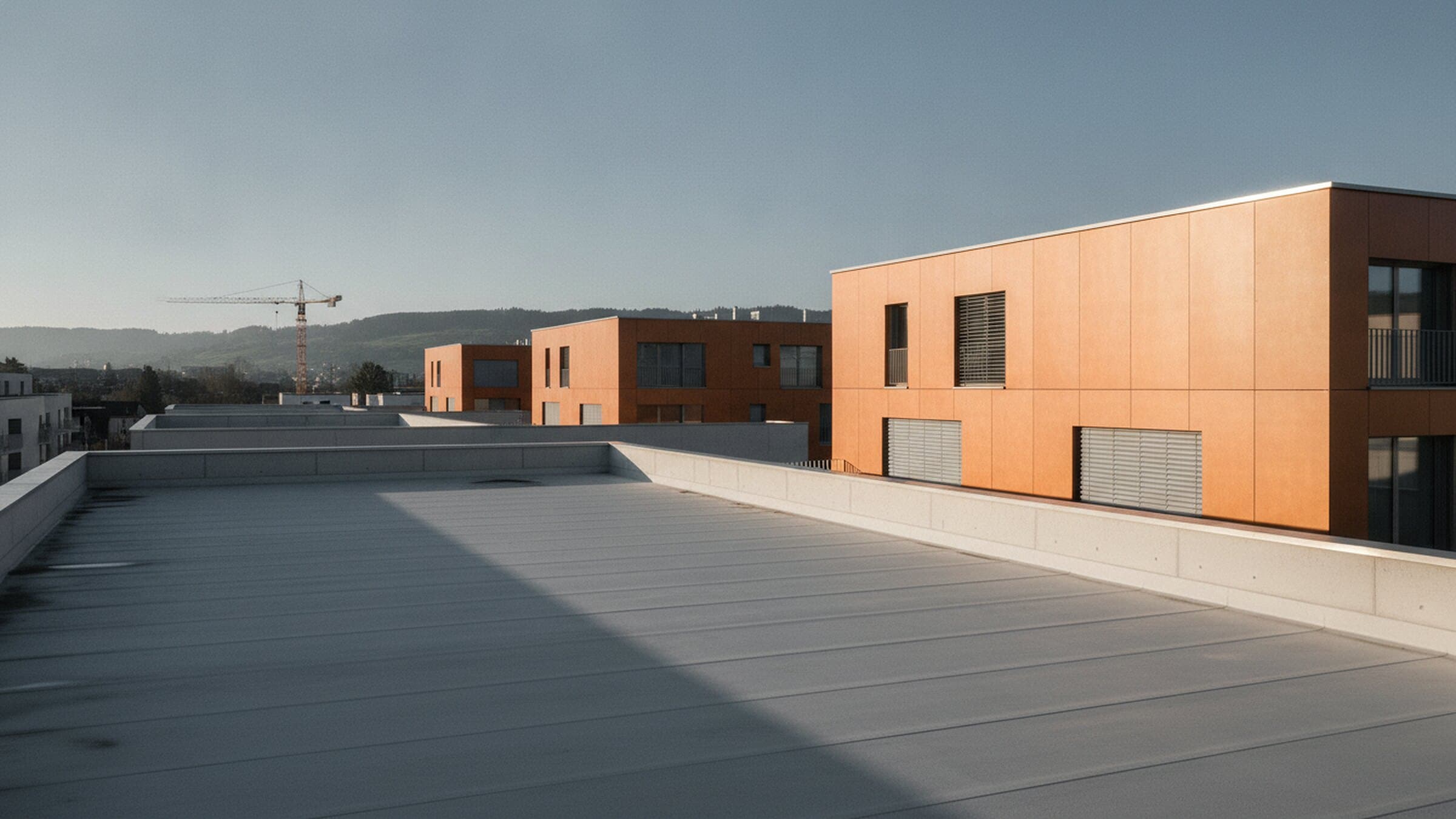 Neu erstellte Wohnüberbauung mit oranger Fassade und Baukran im Schweizer Mittelland
